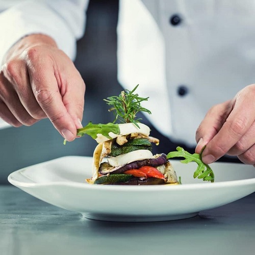 Chefs hands finishing plate for service