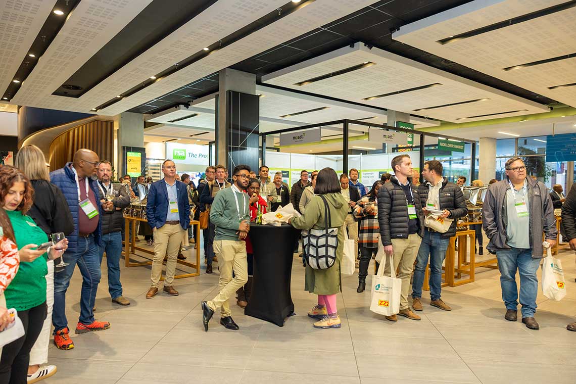 A diverse group of attendees at The Southern Africa Conference in a modern venue with booths and signage.