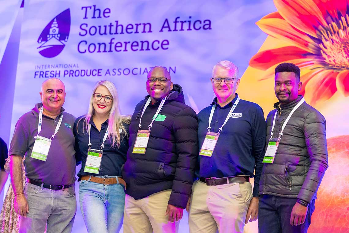 Group of five people at The Southern Africa Conference, standing in front of a colorful floral backdrop.