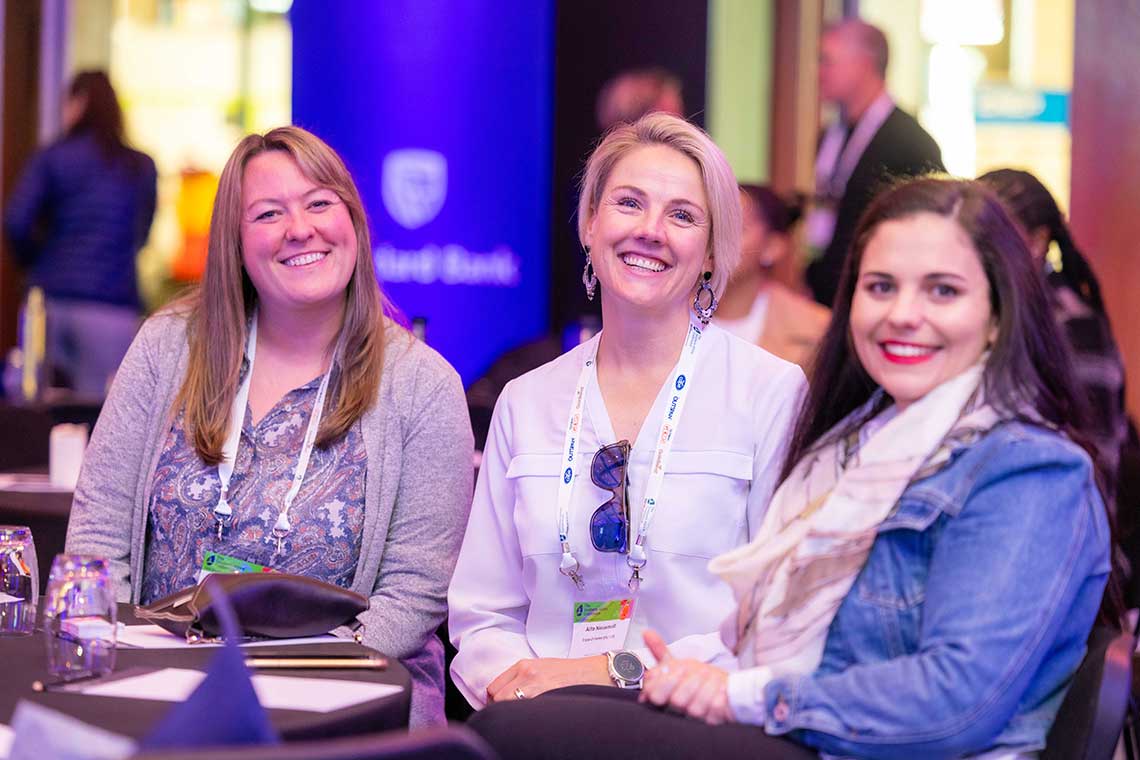 Three women smiling at the Southern Africa Conference by IFPA.