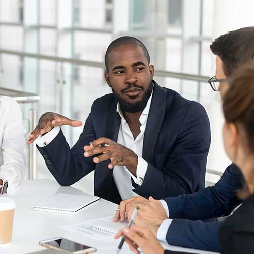 A black male leads a business meeting.