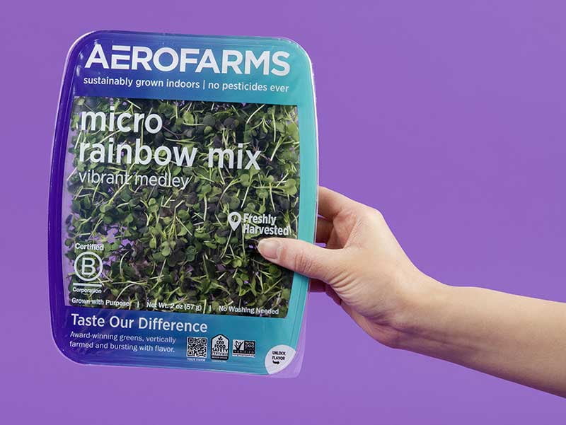 A hand holds a package of Aerofarms micro rainbow mix.