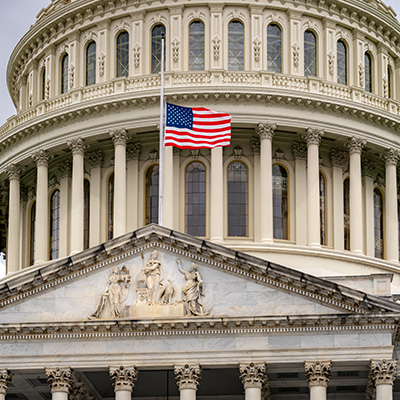 Close-up of the U.S. Capitol dome with an American flag flying in front.